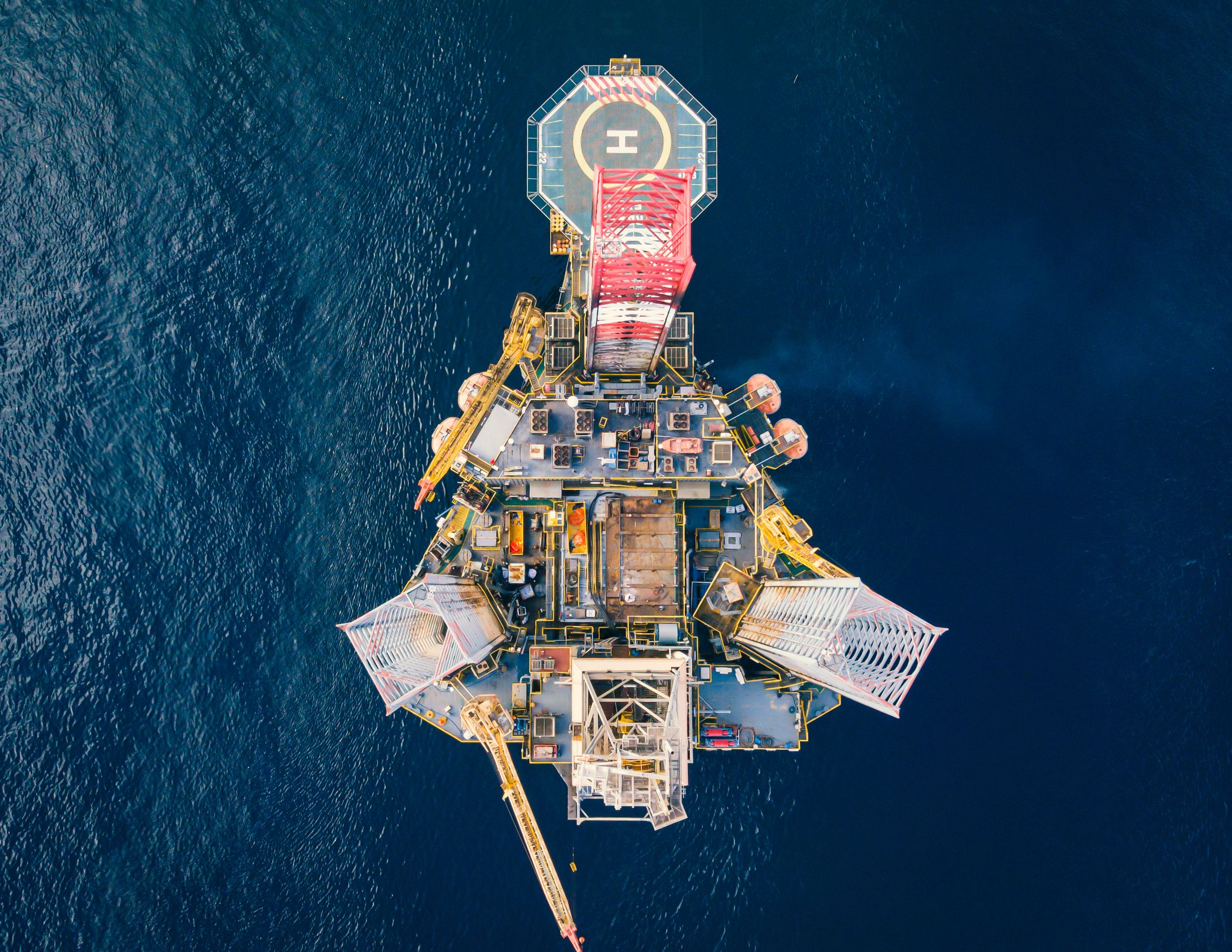 High-angle view of an offshore oil platform with helipad in deep blue sea