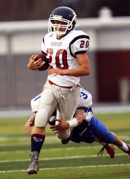 Dynamic shot of high school football players during a game, showcasing a quarterback in action.