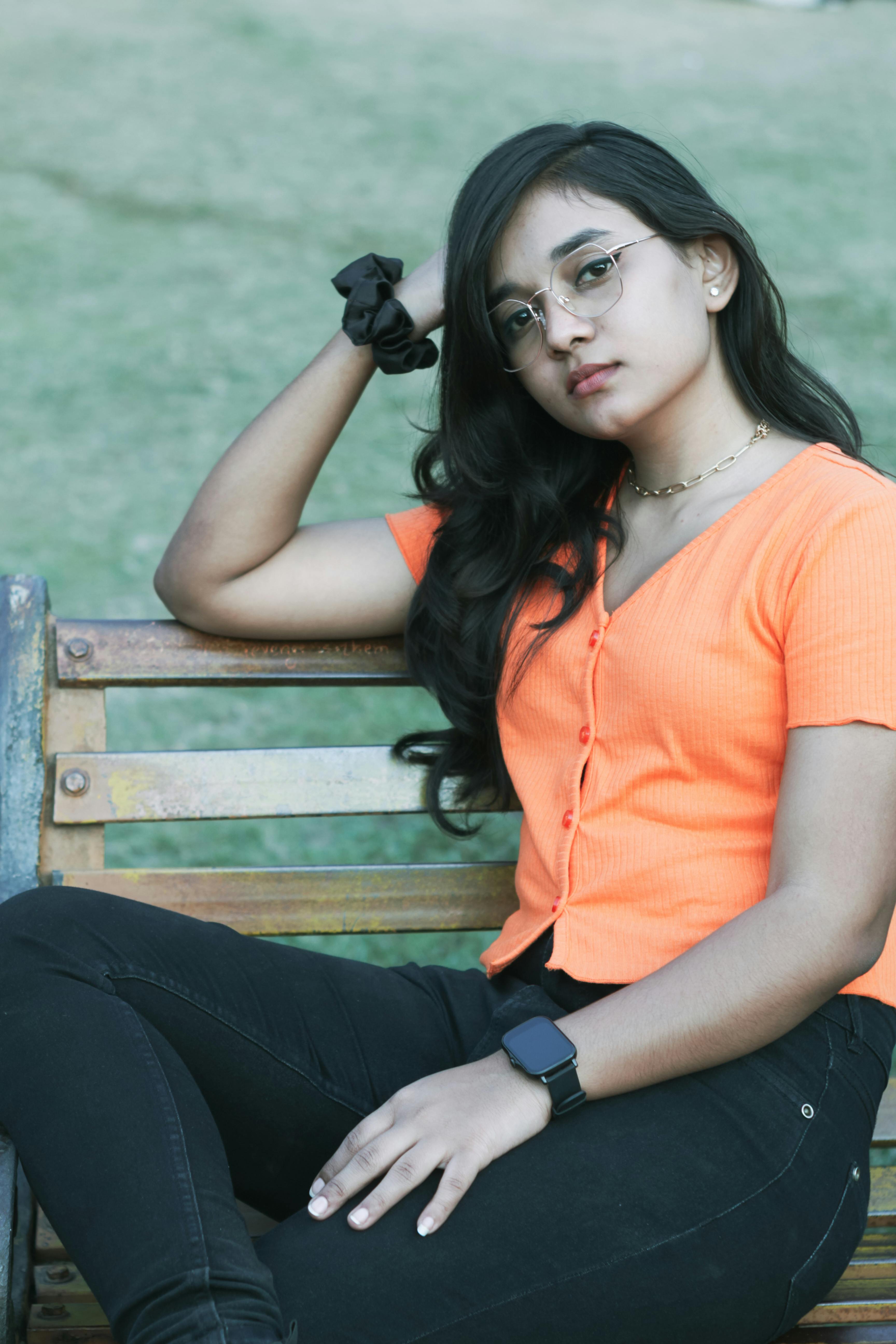 Portrait of a young South Asian woman in casual attire sitting on a park bench in Patna.
