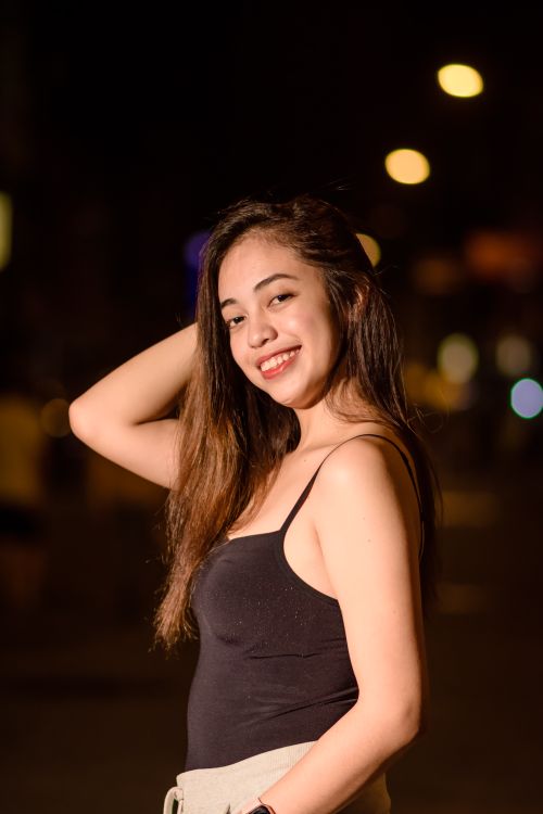 Free Charming young woman with long hair smiling and posing during night outdoors. Stock Photo