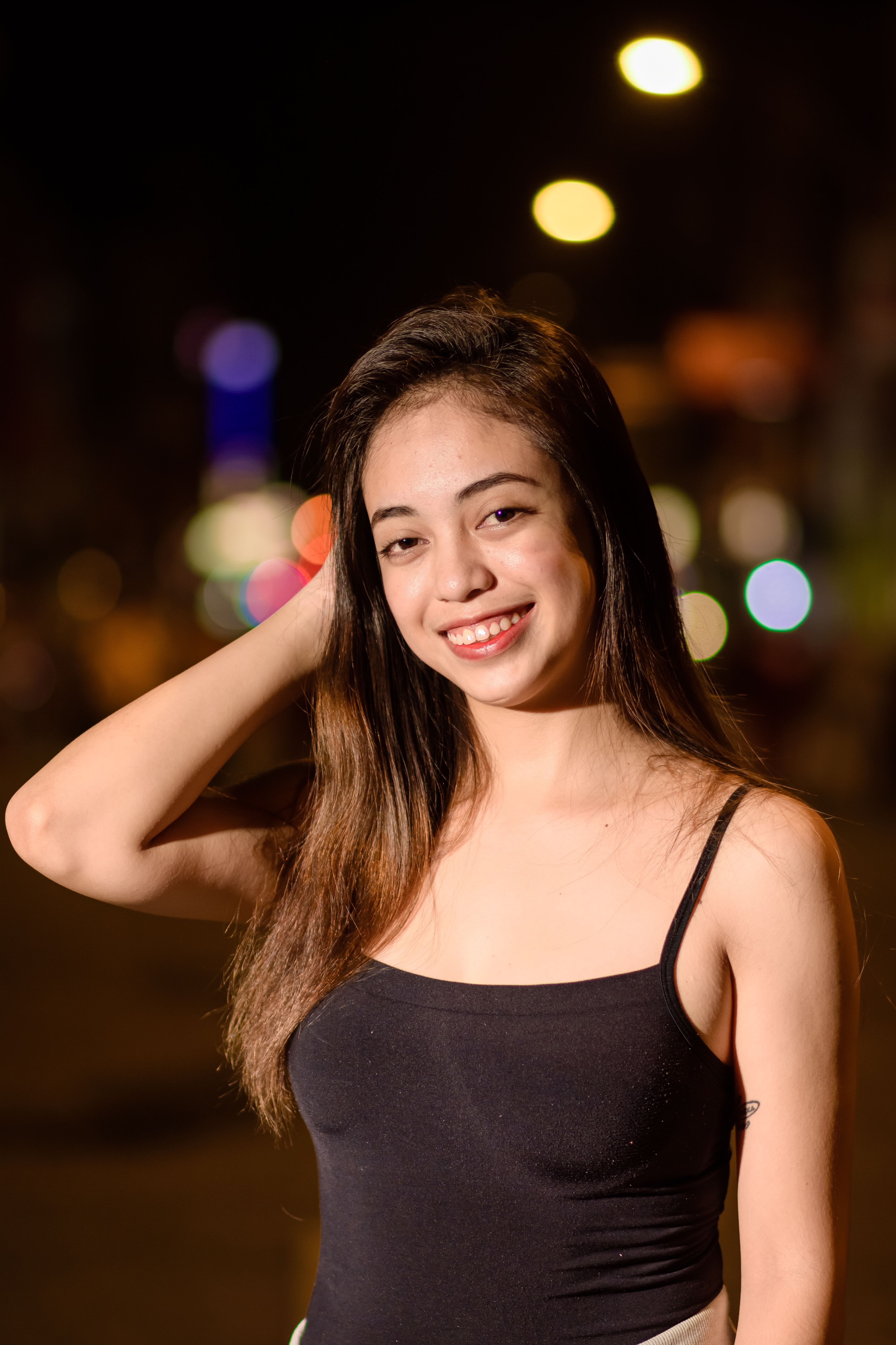 Beautiful young woman with dark hair smiling confidently, enjoying a night out.