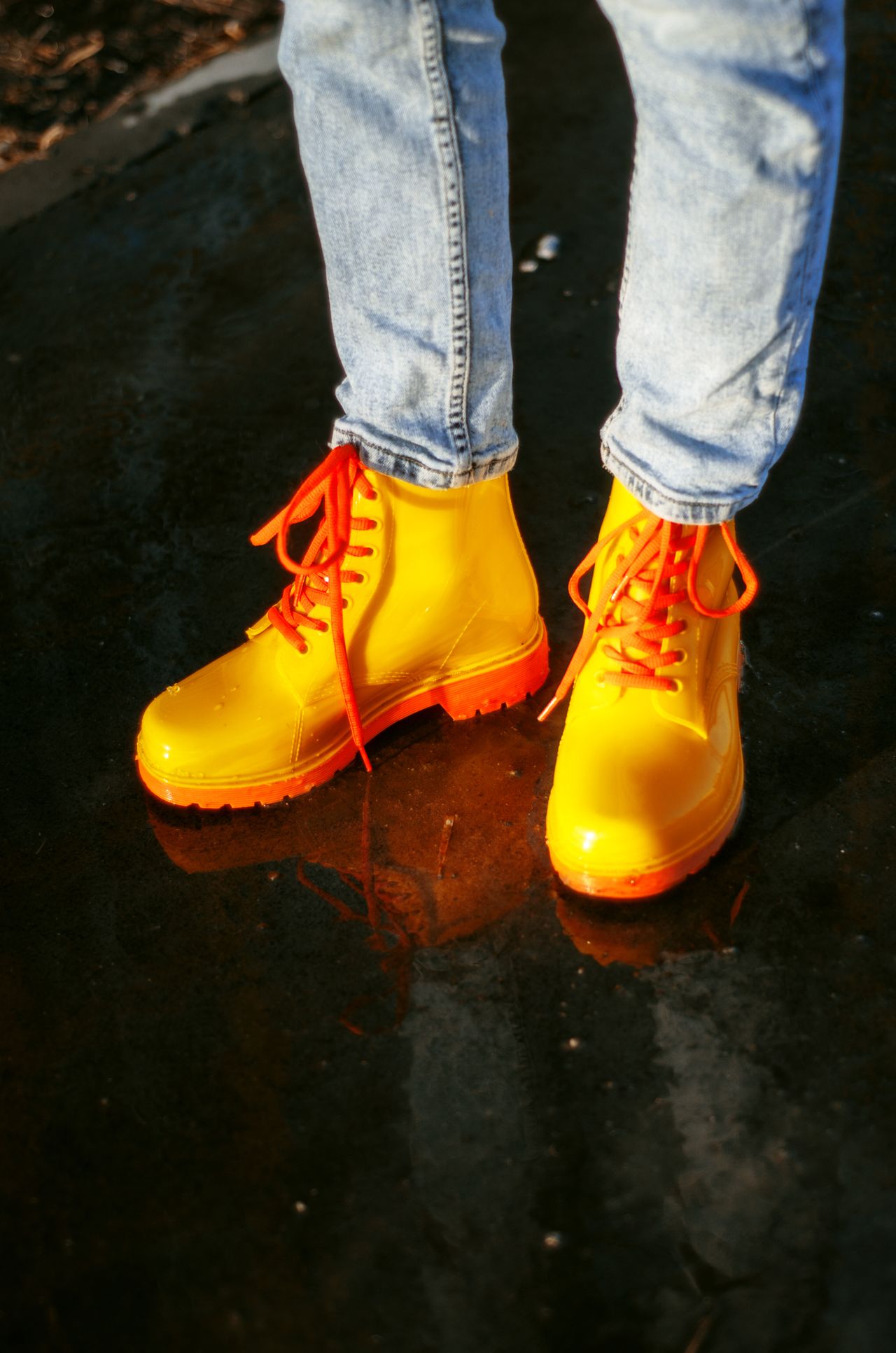 yellow lace-up rain boots on a wet street