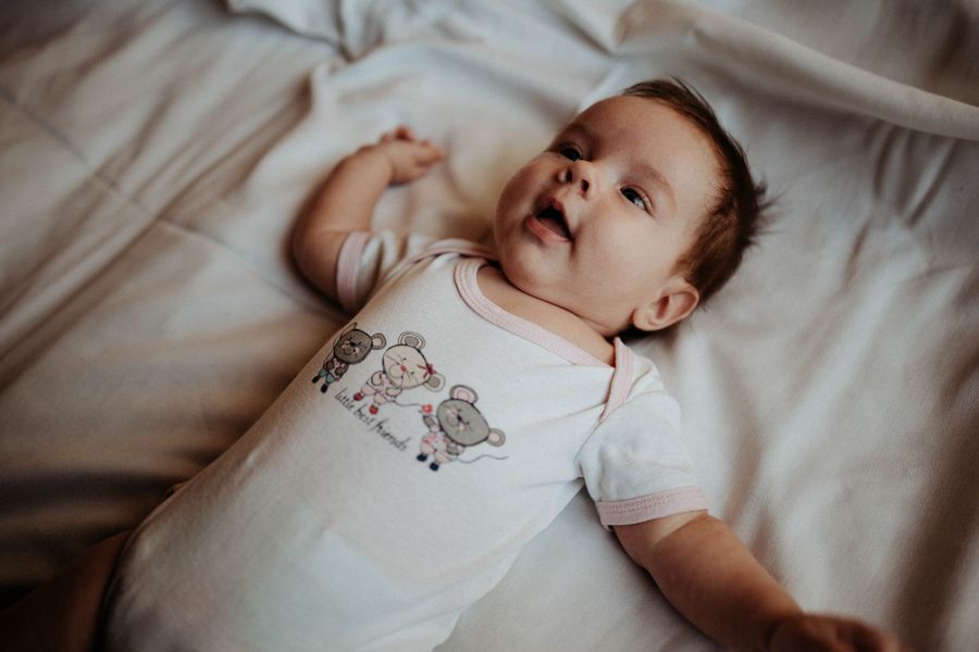 Baby wearing a soft onesie on gentle bedding