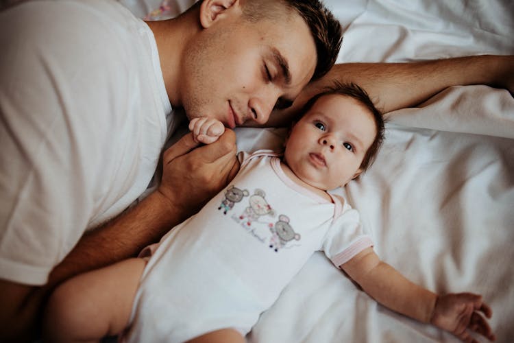 Father Lying On The Bed With His Little Baby 