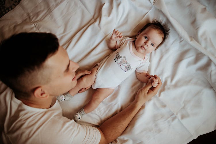 Father Lying On The Bed With His Little Baby 