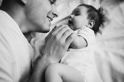 Father Lying on the Bed with His Newborn Baby 