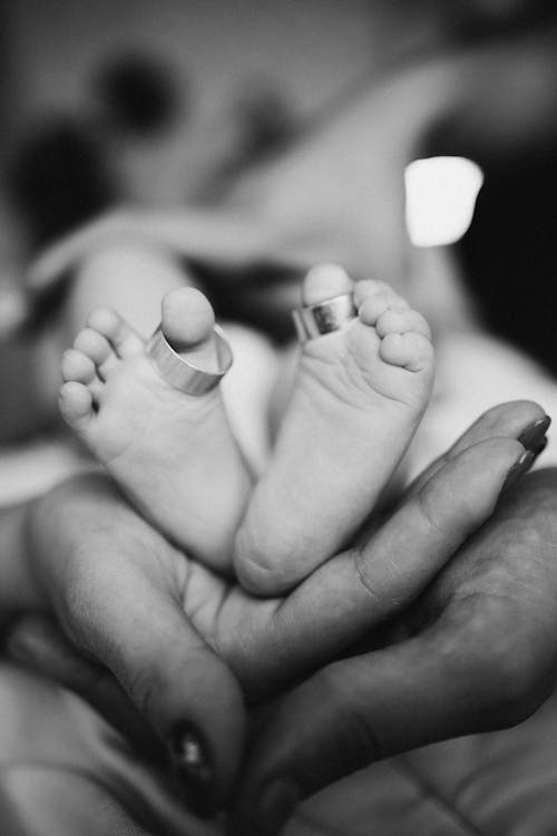 Wedding Rings of the Parents Put on Their Newborn Baby Feet
