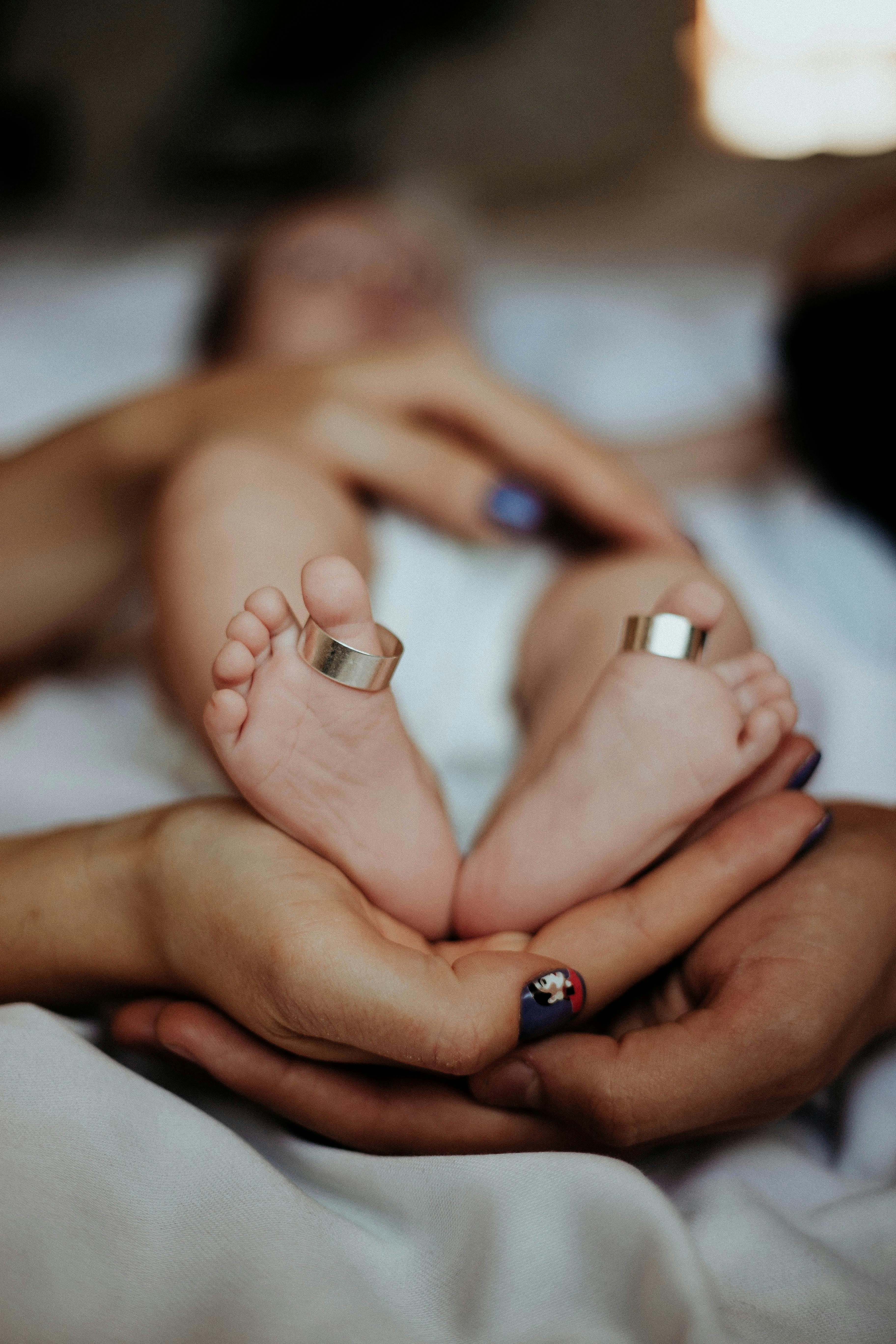 Cherished family moment capturing baby feet adorned with wedding rings, symbolizing love and unity.