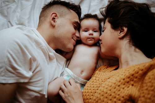 Free A family enjoys a warm, intimate moment lying on the bed with their baby. Stock Photo