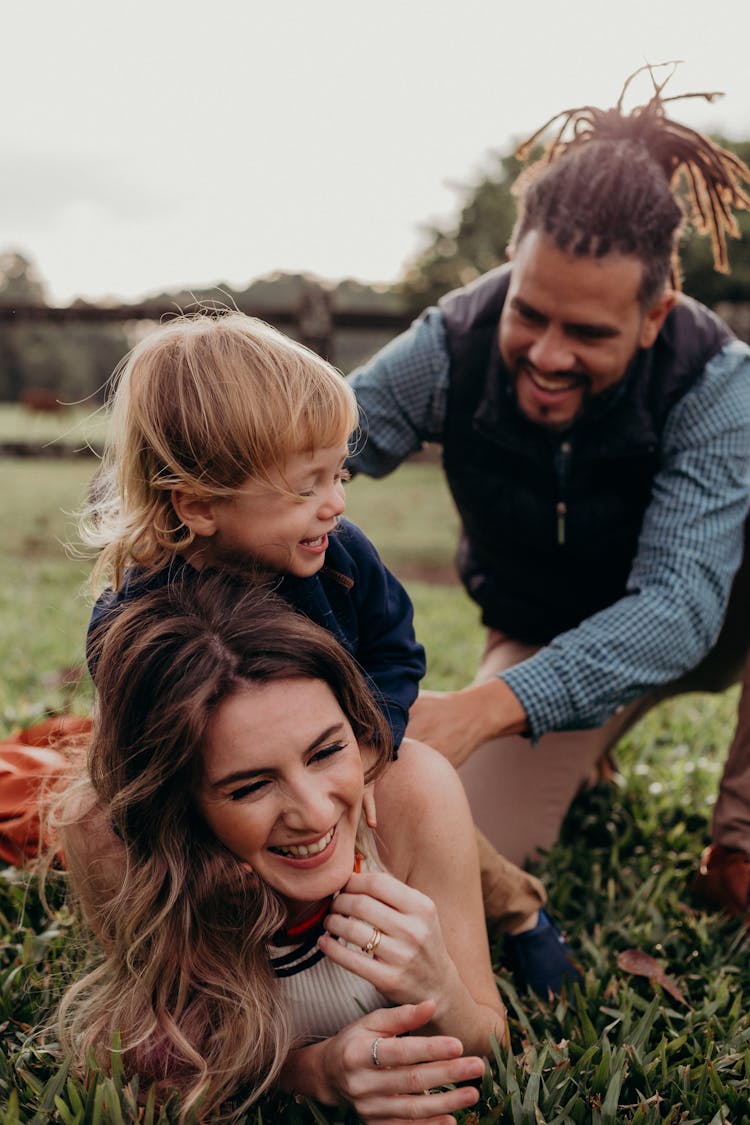 Parents And Their Little Son Playing Outdoors And Laughing