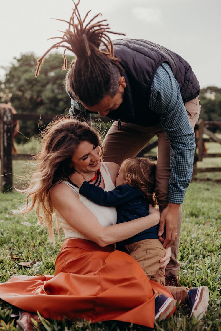 Parents And Their Little Son Playing Outdoors And Laughing 