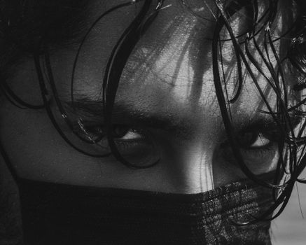 Intense black and white close-up portrait of a man with wet hair wearing a face mask.