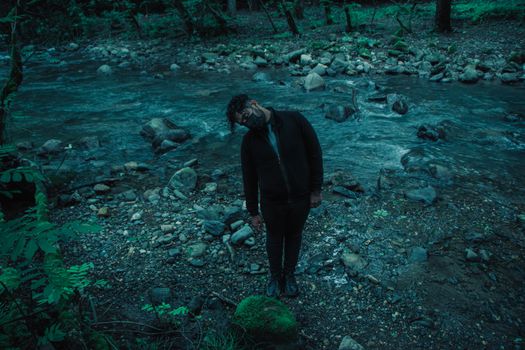 Man Wearing Face Mask with Crocked Neck Standing on Riverbank 