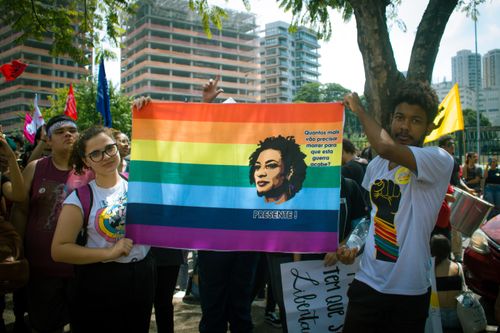 Free Colorful pride parade featuring diverse crowd holding a statement banner on city streets. Stock Photo