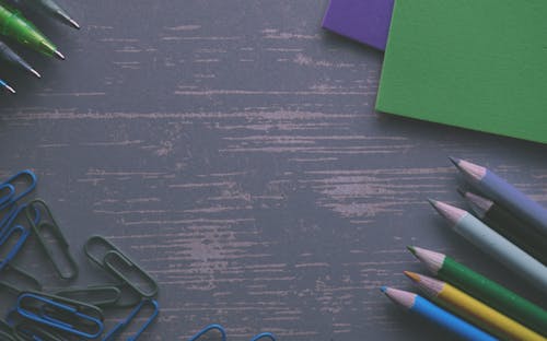 Free Colored Pencils on a Gray Desk With Paper Clips and Folders Stock Photo