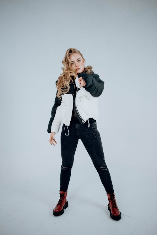 Young Woman Wearing a Jacket and Boots Posing in a Studio 
