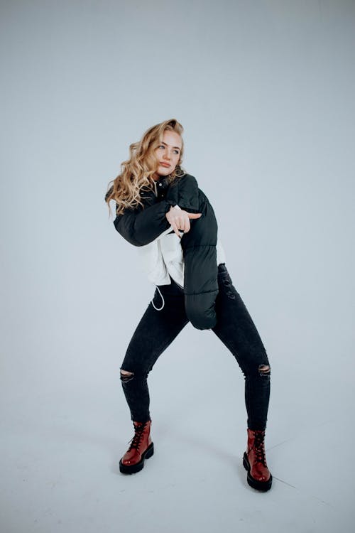 Young Woman Wearing a Jacket and Boots Posing in a Studio 