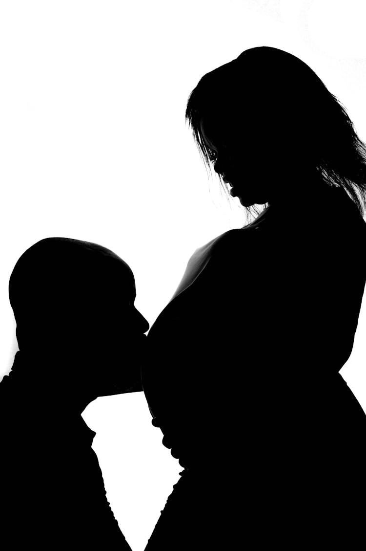 Silhouette Of A Man Kissing A Pregnant Woman Belly 