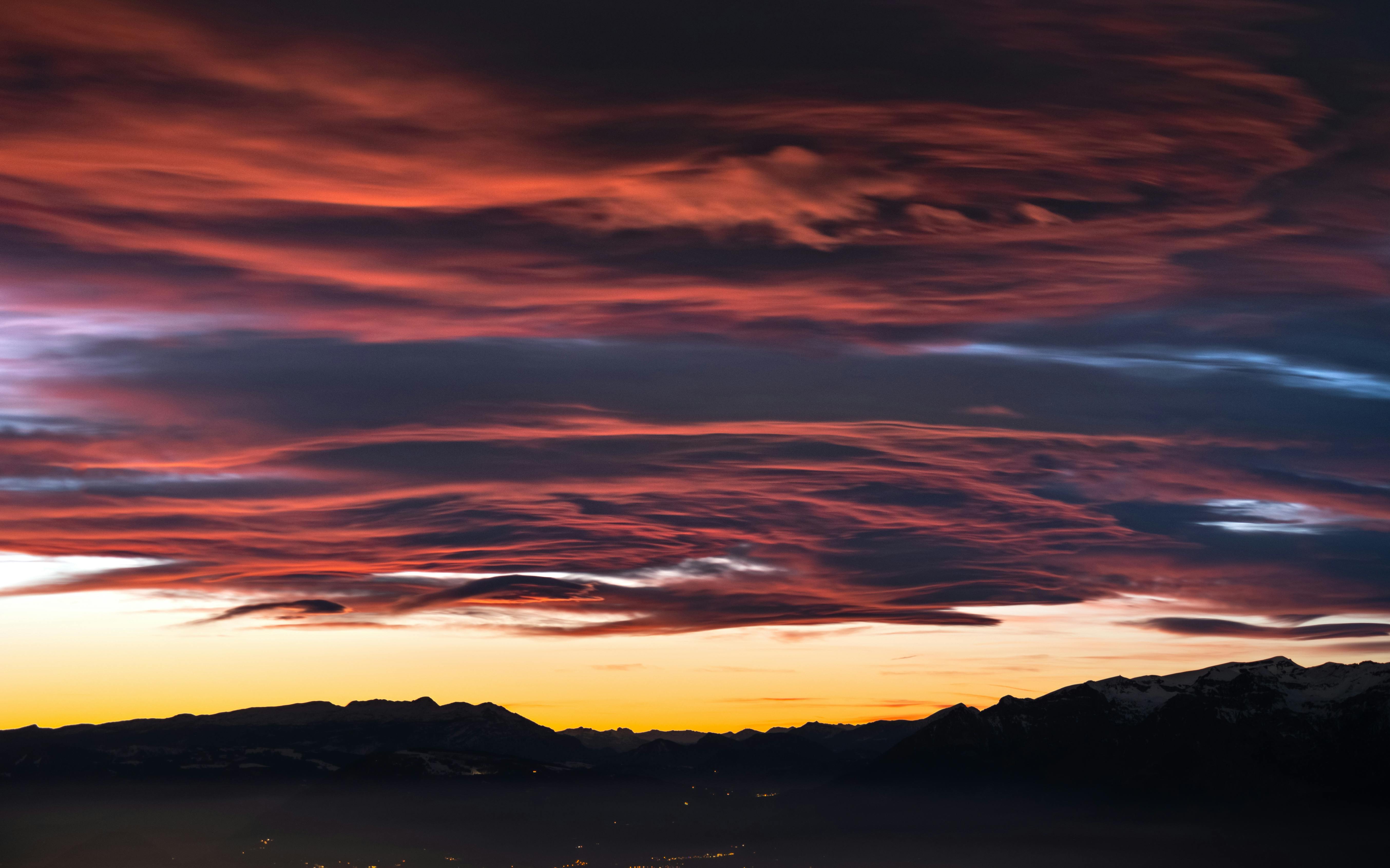 Stunning sunset with vibrant clouds over a mountain range, capturing nature's drama.