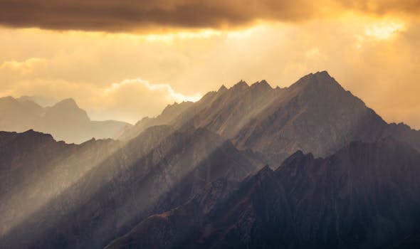 A breathtaking view of sun rays illuminating the Italian Alps at sunset.