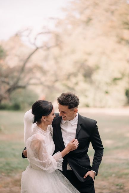 A romantic moment between a bride and groom embracing outdoors in a sunlit garden.