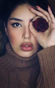 Close-up of a woman with a rose over her eye, showcasing elegance and beauty.