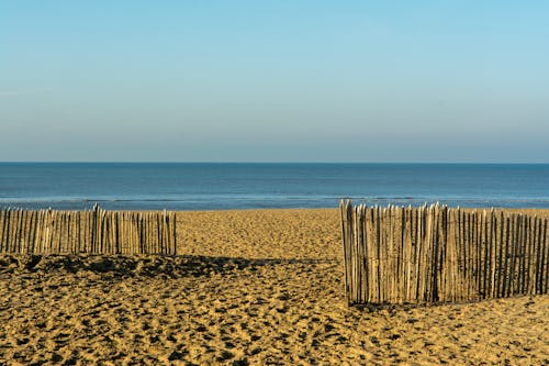 A Wooden Fence on the Beach and a Seascape under a Blue Sky 