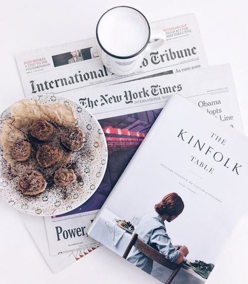 Le Livre De Table Kinfolk à Côté De La Pâtisserie Cuite Au Four Sur Une Plaque En Céramique Blanche Avec Une Tasse En Céramique Blanche