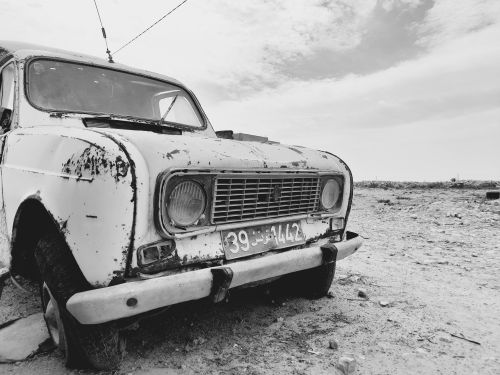 Free Black and white image of a vintage car wreck in the Tunis desert. Evokes nostalgia and decay. Stock Photo