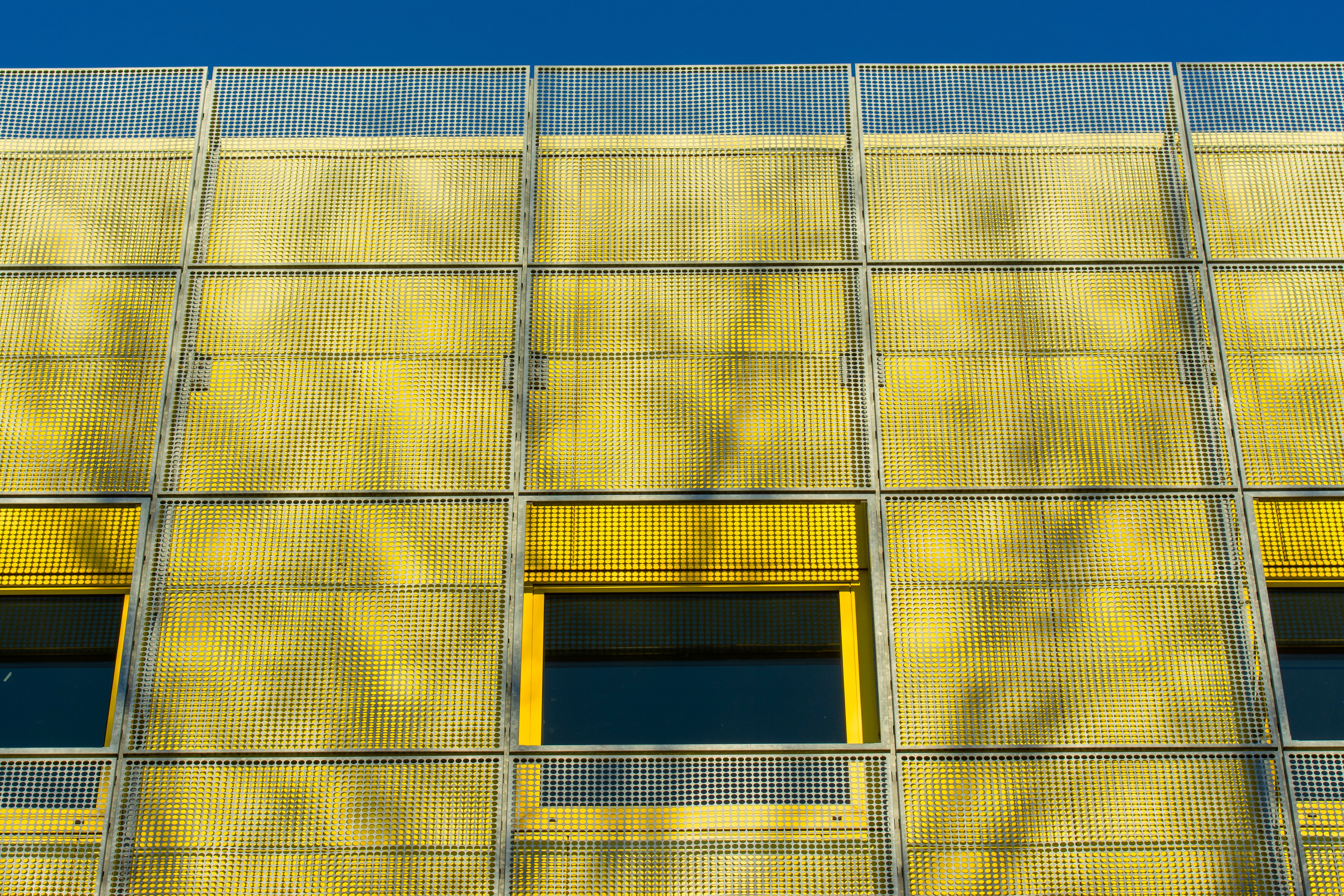 Low angle view of a yellow building facade featuring unique architectural patterns in Zoetermeer, Netherlands.
