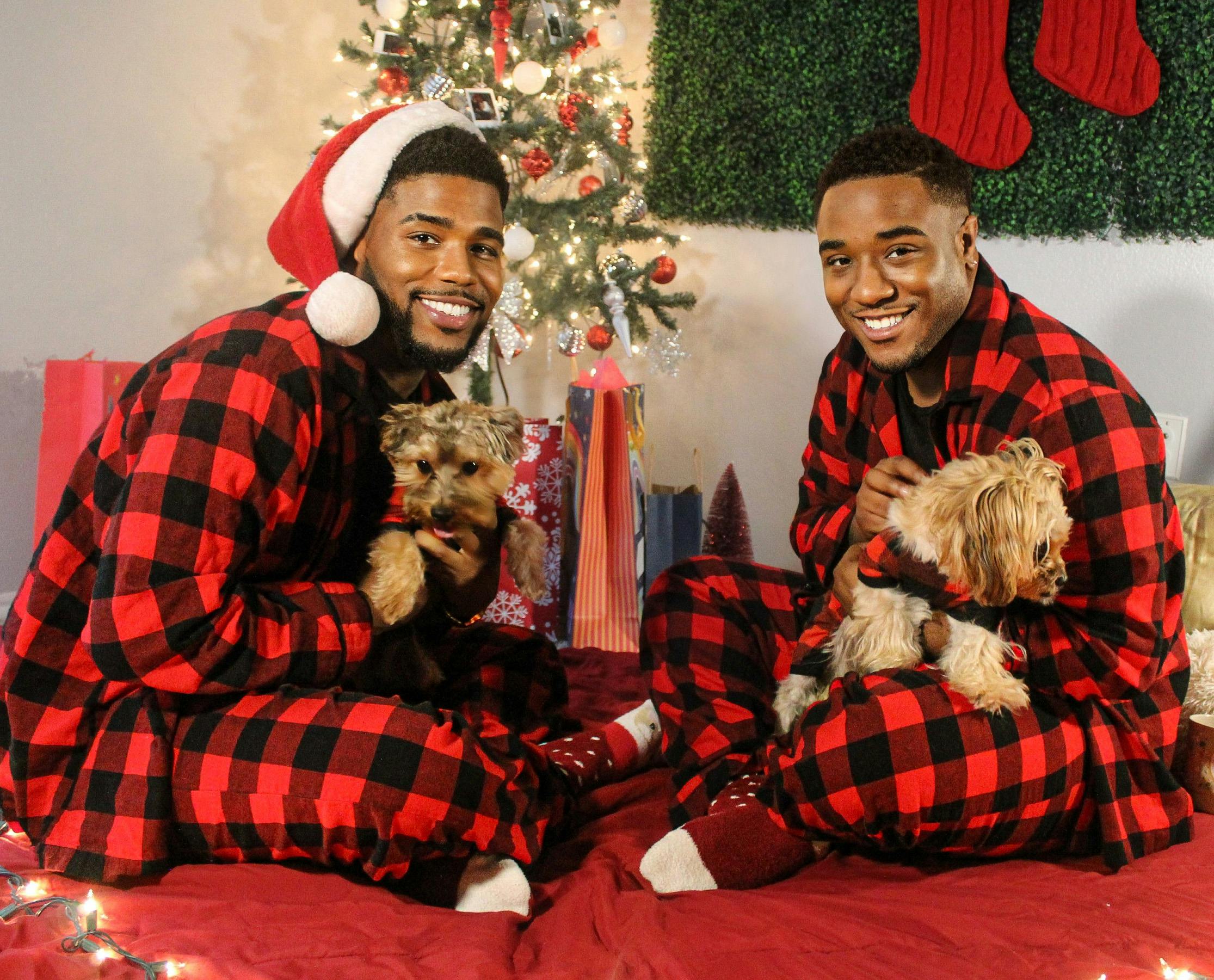 A Couple in Matching Pajamas Sitting by a Christmas Tree with Dogs Free Stock Photo