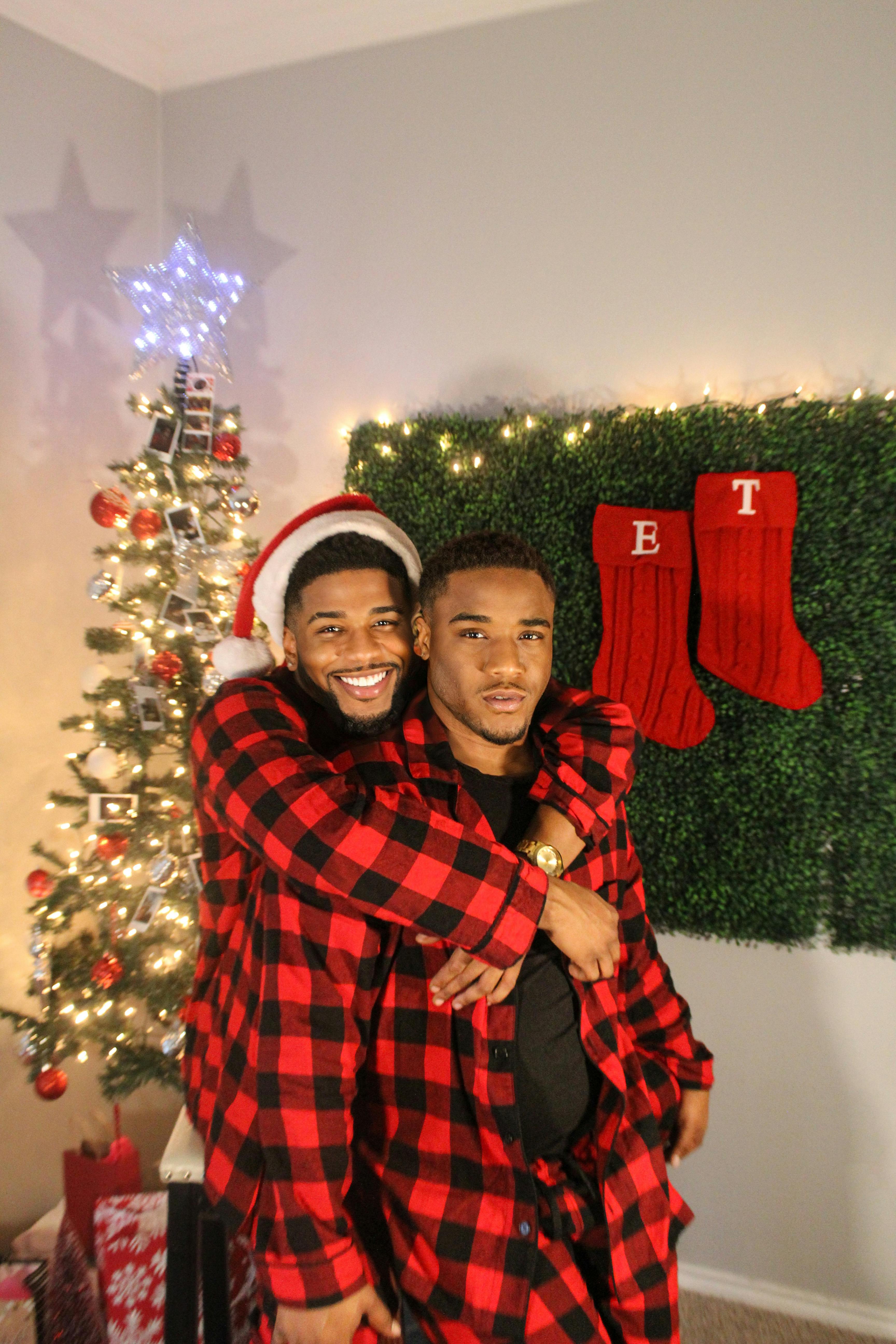 A Couple in Matching Pajamas Sitting by a Christmas Tree with Dogs