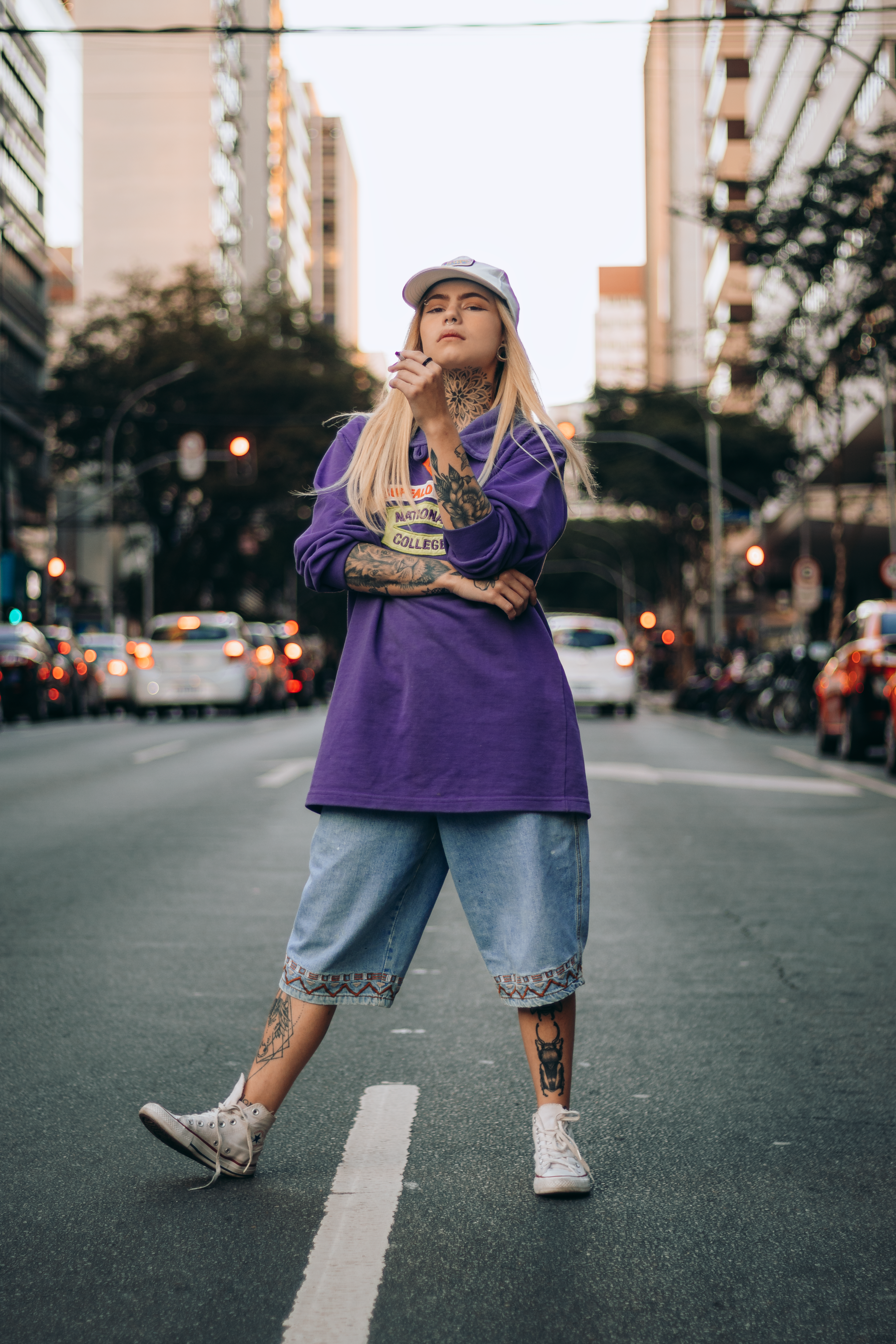 Jovem mulher confiante posando na rua da cidade, vestindo roupa casual e um boné.