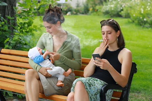 Women Sitting with Baby and Smoking at Park