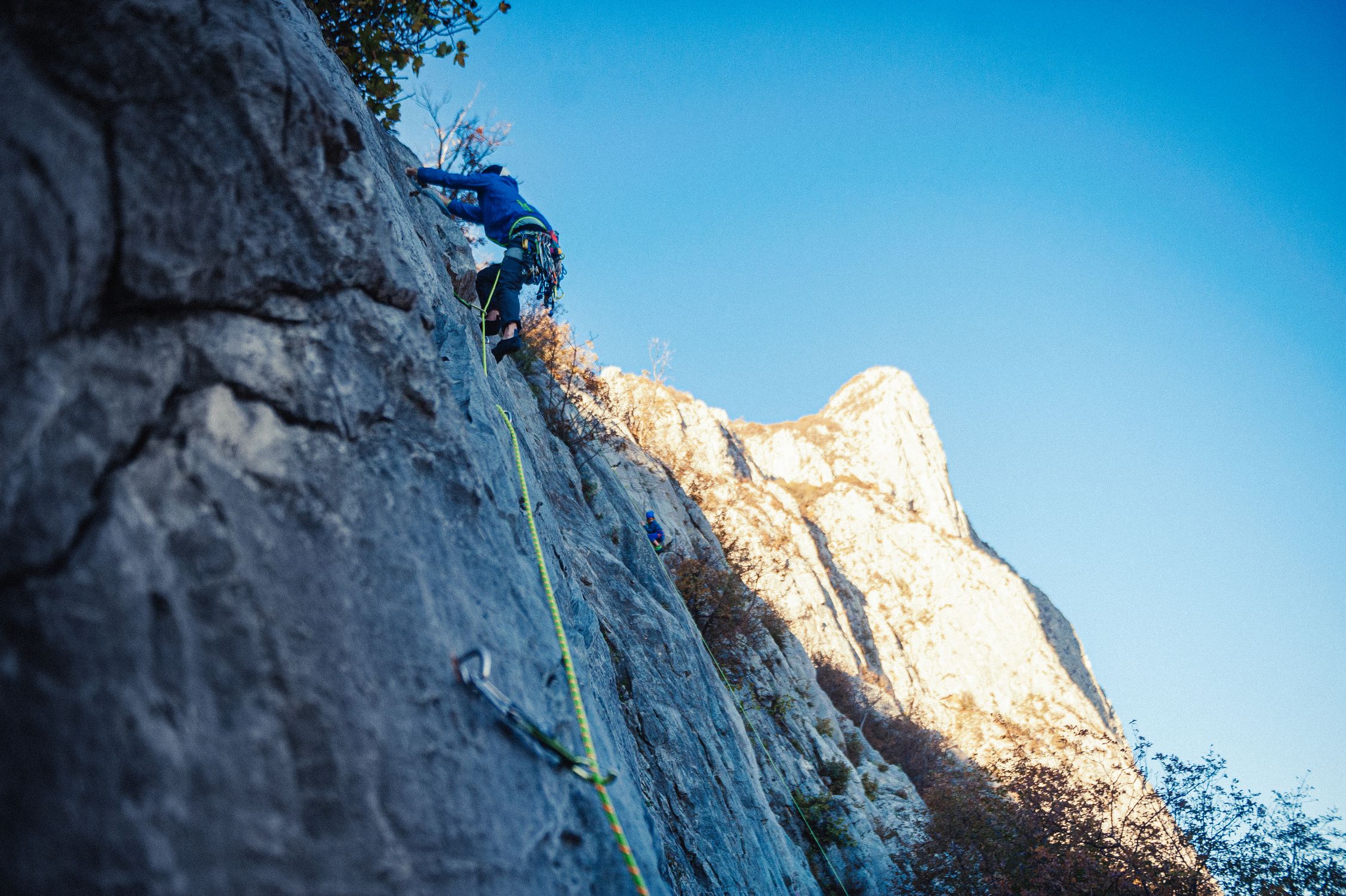 Adventure climber on steep sun-lit rock face with harness and helmet