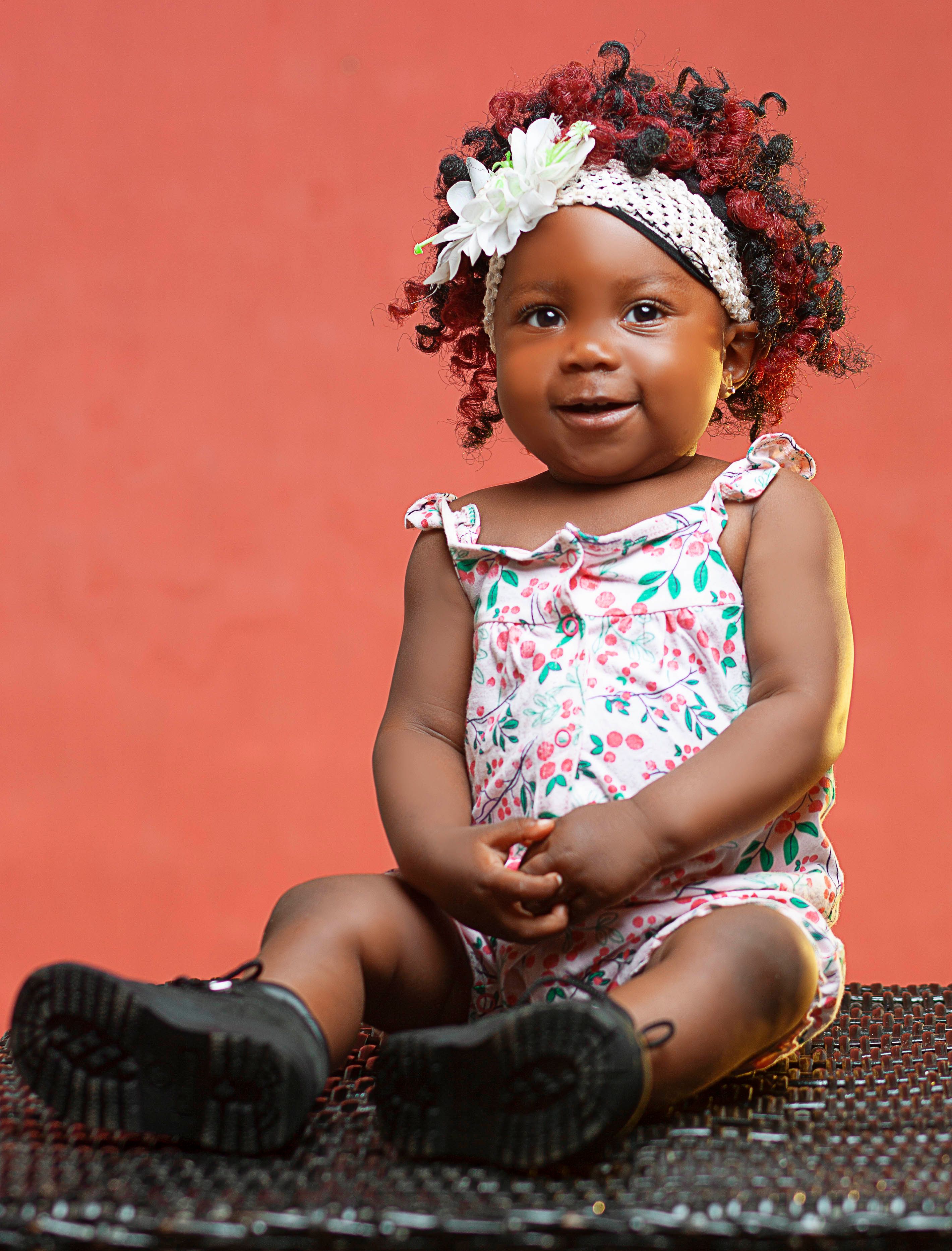 Cute baby girl smiling while sitting in a studio with a vibrant background.