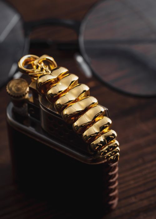 Free Close-up of luxurious golden pendant shaped like a rattlesnake tail on a dark surface. Stock Photo
