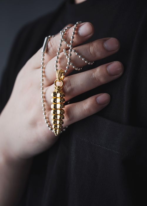 Free Close-up of a hand holding a golden rattlesnake pendant on a necklace. Stock Photo