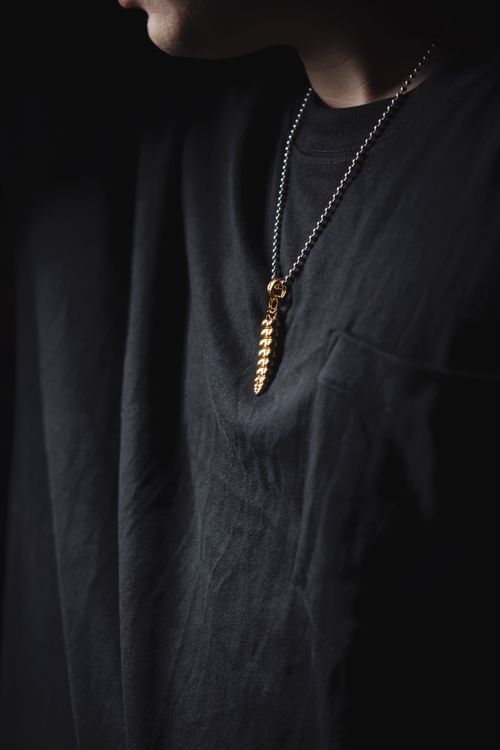 Free Elegant golden necklace pendant with black shirt background, dark moody aesthetics. Stock Photo
