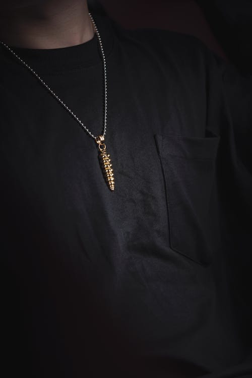 Golden Pendant on Person in Black T-Shirt