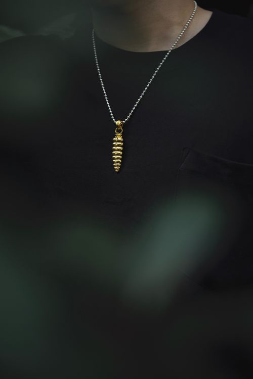 Free Stylish gold pendant necklace on black clothing, capturing a modern minimalistic vibe. Stock Photo
