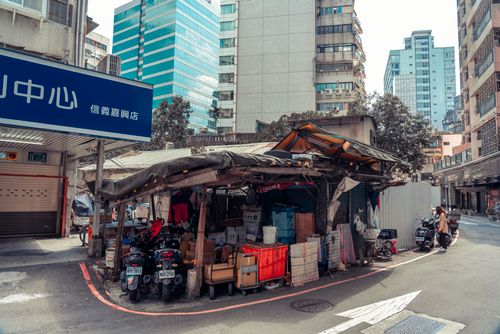 Free City street market with scooters parked, surrounded by tall buildings under a bright sky. Stock Photo