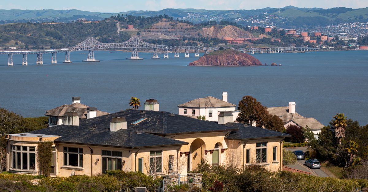 A picturesque view of San Francisco Bay with a bridge and luxurious homes in the foreground.