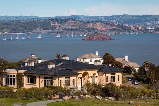 A picturesque view of San Francisco Bay with a bridge and luxurious homes in the foreground.