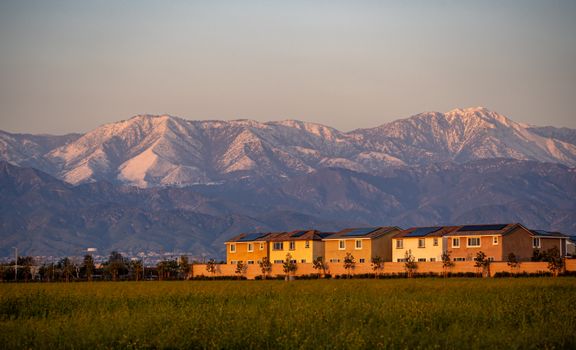 Houses near Redlands, CA, with San Bernardino Mountains at sunset.