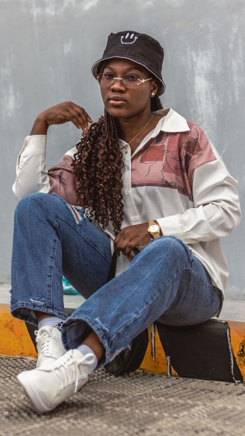 Free A fashionable young woman with eyeglasses and a hat poses outdoors in casual attire. Stock Photo