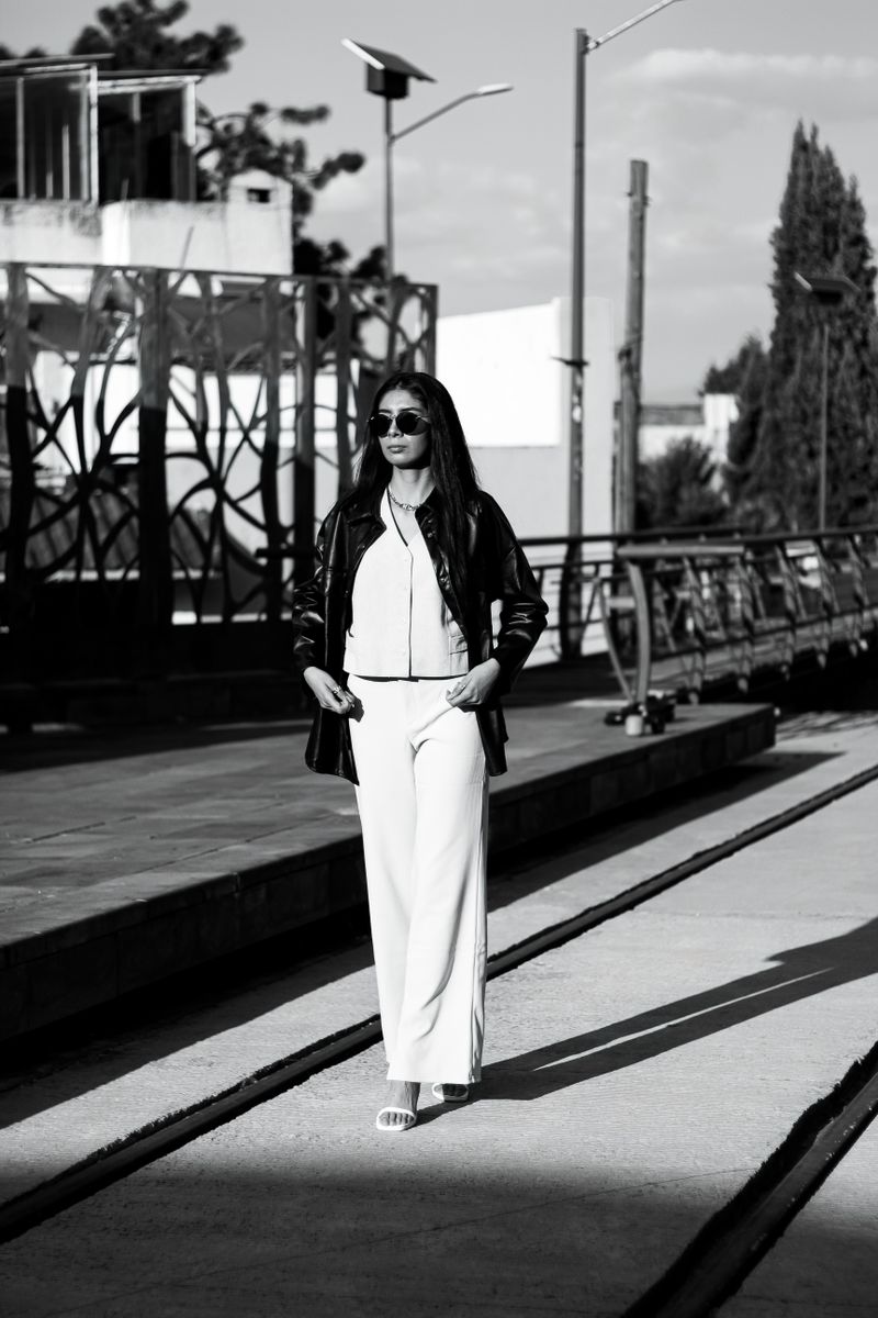 Model in white wide trousers and a black jacket, black and white photo