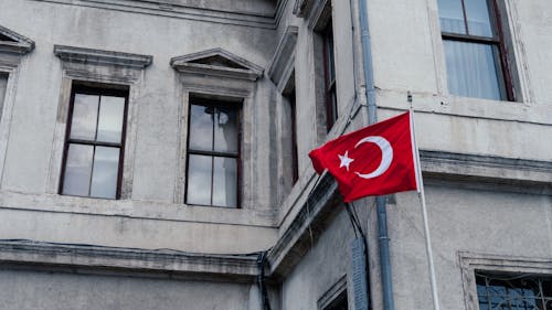 Turkish Flag on Pole by Gray Building