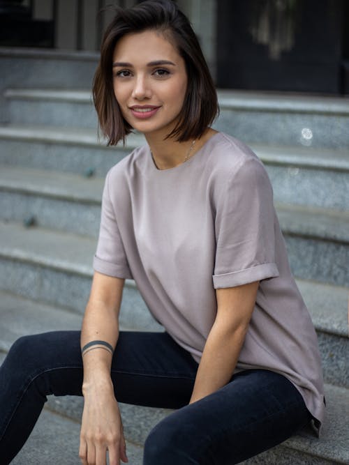 Young Brunette Woman in T-Shirt Sitting on Stairs on Street