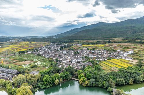 Free Drone shot of a picturesque rural town surrounded by lush fields and hills. Stock Photo